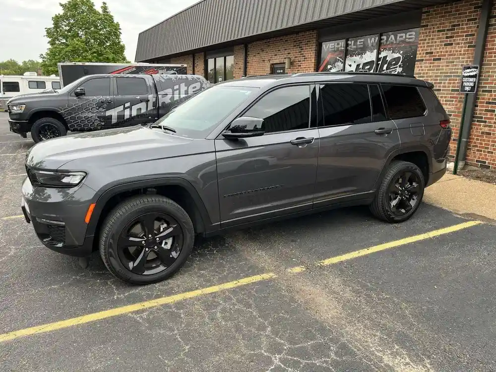 Gray Jeep Grand Cherokee L with dark rear privacy tint and lighter front windows