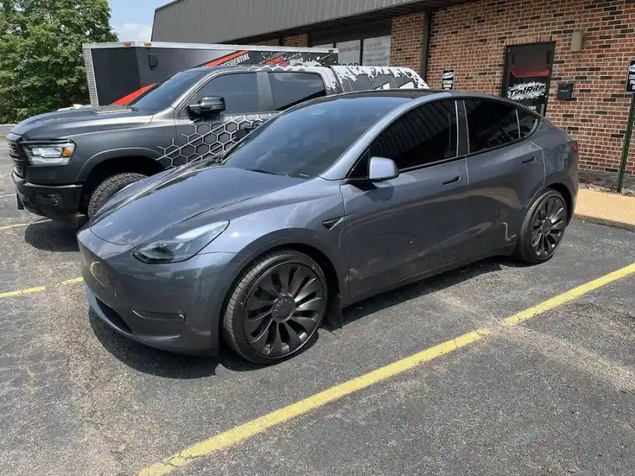 Gray Tesla Model Y with tinted windows parked outside the shop