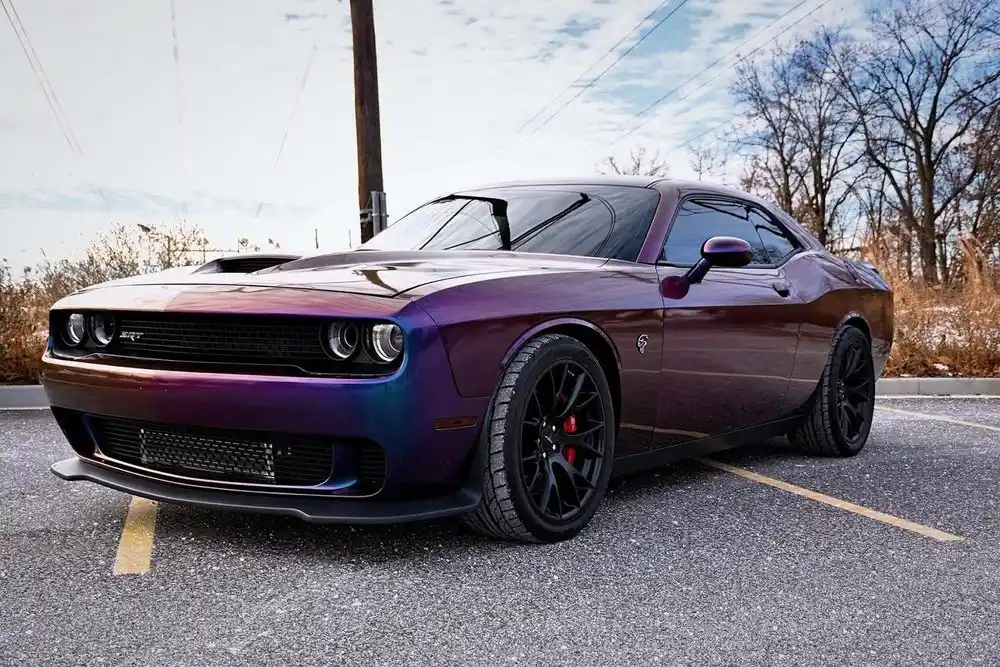 Purple Dodge Challenger SRT with tinted side glass parked on a gravel lot