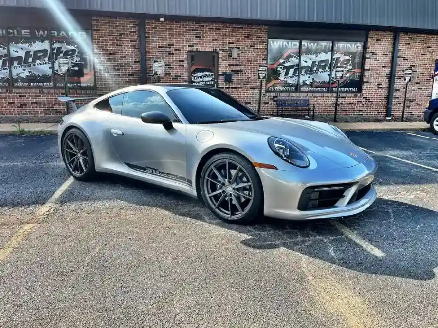 Silver Porsche 911 Carrera T with tinted side windows in front of the shop